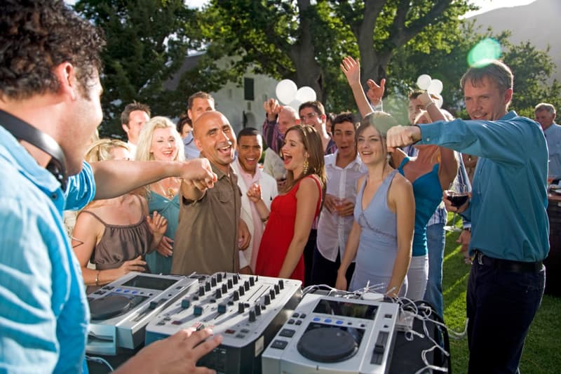 A DJ at an outdoor party with guests dancing