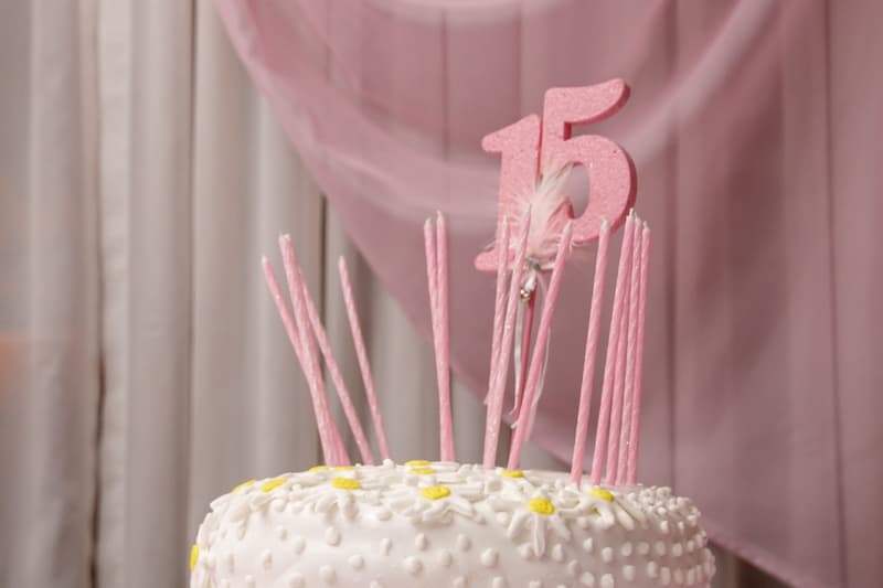A pink birthday cake topped with a number 15